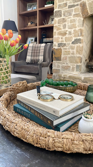 Coffee table decor including a rattan hurricane vase with a bright tulip floral arrangement