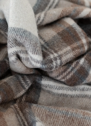 Close up of neutral tartan plaid blanket with shades of cream and chocolate brown